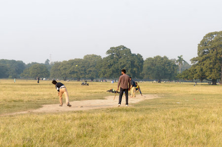 Local Indian boys having fun playing cricket game in Maidan area in the winter sunset evening time...