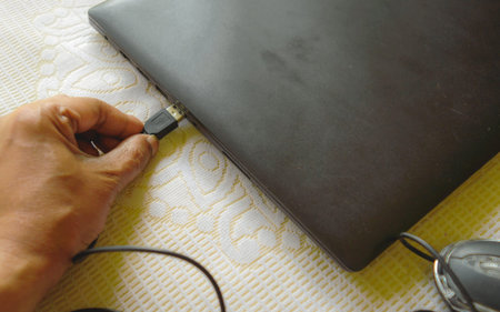 Human hand connecting Computer mouse connection cable plug-in the laptop keyboard. Network...