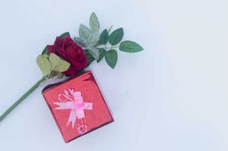 Gift box wrapped and tied with ribbon and a red rose in white background. Table top view. Vertical. Copy Space.の写真素材