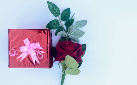 Gift box with a ribbon and a red rose in white background. Table top view. Copy Space.の写真素材
