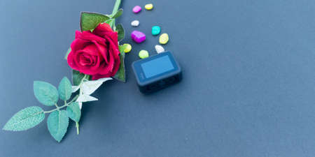 A camera laid on a Blue color wooden table with a red rose. Kolkata India 10th September 2021の写真素材