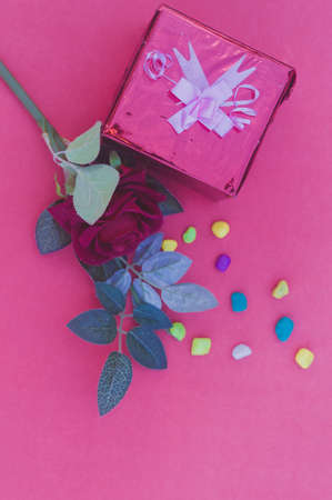 A gift box tied bow with ribbon and a red rose on table in red background. Flat lay Vertical. Top View. Design for valentine's day, anniversary or holiday celebration decoration. Copy space for text.の写真素材