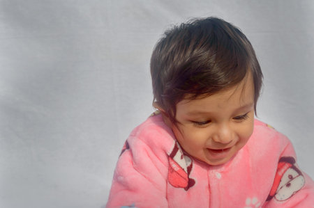Close-up Portrait of happy Baby Wearing pink Velvet warm clothes on white background. Cute Baby in...