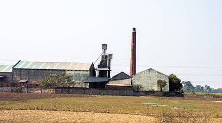 Industrial Factory Building landscape against clear sky background and agriculture field in the foreground.の写真素材