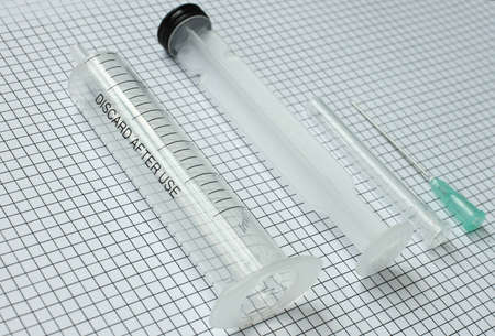 disassembled medical syringe on graph paper. the concept of mechanics, physics, engineering.の写真素材