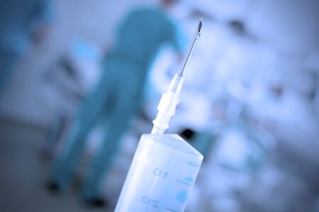 Syringe as a symbol of medicine. Photo of medical needle against hospital ward. Stylized toned photos.の写真素材