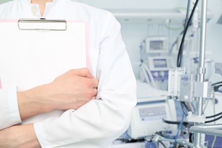 Doctor in white coat with a clipboard on a background of a hospital ward の写真素材