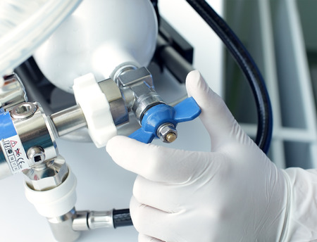 Hand in glove turns the valve on the oxygen cylinderの写真素材