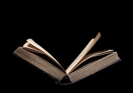 Old book open to study isolated on a black background