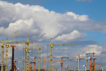 Building cranes on a large construction site on a background of thick cloudsの写真素材