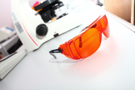 Protective glasses in a scientific laboratory microscope on background conceptの写真素材