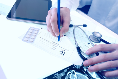 Doctor writing prescription form in his officeの写真素材
