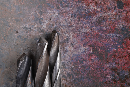Steel drill bits on rusty iron background.の写真素材