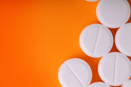 White pills on an orange background.の写真素材