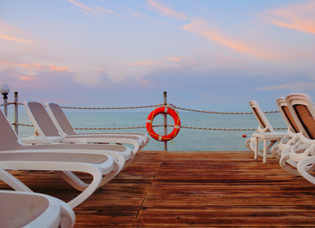 Sunbeds on a wooden deck at the sea.の写真素材