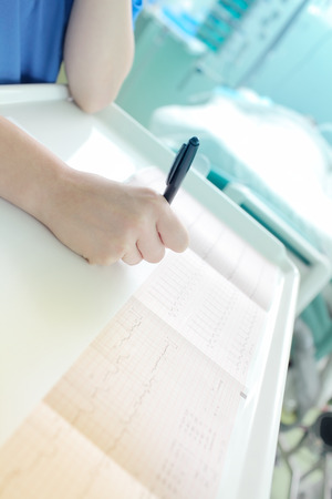 Doctor intently examines a cardiogram at the hospital.の写真素材