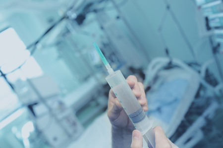 Full syringe on the background of patient's bed.の写真素材