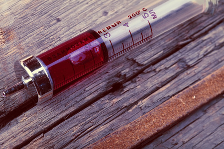 Old glass syringe on the grunge wooden surface.の写真素材