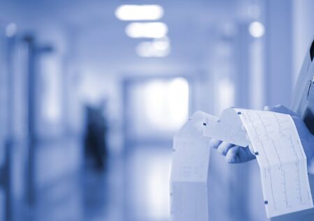 Male doctor examines the patient's ECG trace in the hospital corridor.の写真素材