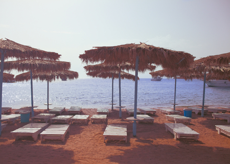 Sand beach witrh wooden sun loungers and thatch beach umbrellas.の写真素材