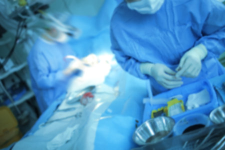 Surgeon with assistant nurse performs the emergency surgical procedure to the patient, unfocused...