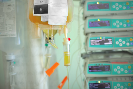 Blood plasma bag dripping to the patient on the background og medical equipment.の写真素材