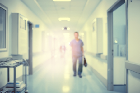 Hospital hallway with the silhouette of a medical doctor in the rays of a mysterious light, defocused backgroundの写真素材