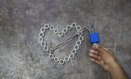 The nut heart with blue key on the metal background. The nut heart is locked for valentines day.の写真素材