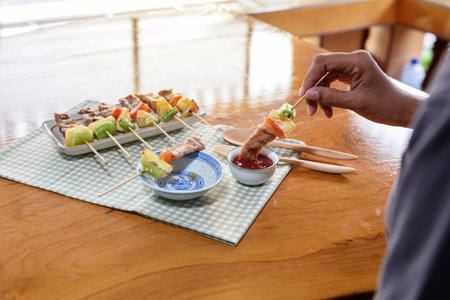 Closed up of girl is eating pork Bar B Que(BBQ) with vegetable(Bell pepper,tomato,pineapple) and tomato sauceの写真素材