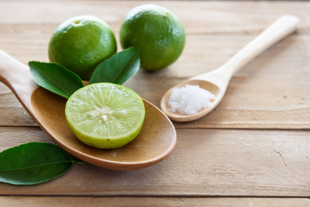 Lemons with green leaf in spoon on wooden backgroundの写真素材