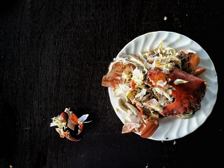 left over food trash, crab shell on a plate from a streamed crab on dark wood table.の写真素材