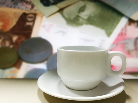 coffee cup and pile of international banknote in the background. business concept.の写真素材