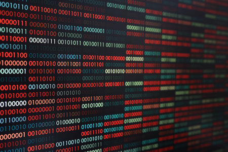 Computer virus infection. Row of binary codes randomly colored red and blue on black screen monitor...