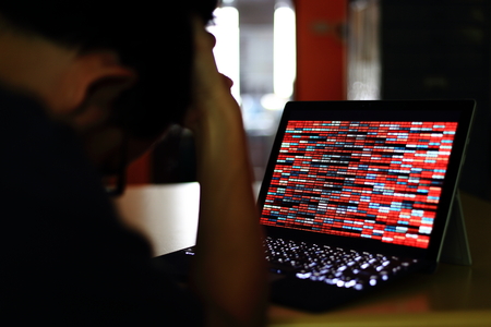 Computer Hacker silhouette typing on computer in a dark room. Working on binary code technology. binary data, computer crime and network security concepts.の写真素材