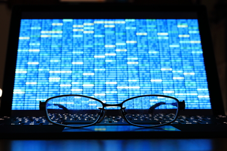 Glasses in front of laptop monitor. digital screen displayed blue light code blocks. computer language coding development concept. back of the house big data work environment.の写真素材