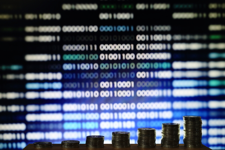 coin stacked columns pile in front of out of focus computer screen displayed blue code matrix. online marketing innovation idea.の写真素材