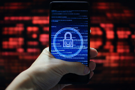 system integrity working while other pass down. hand holding mobile phone with padlock icon on blue binary code screen. Error message in computer screen in the background.の写真素材