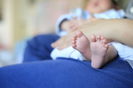 small Baby feet resting on mother leg. soft smooth skin of infant. baby sitting on mother lap.の写真素材