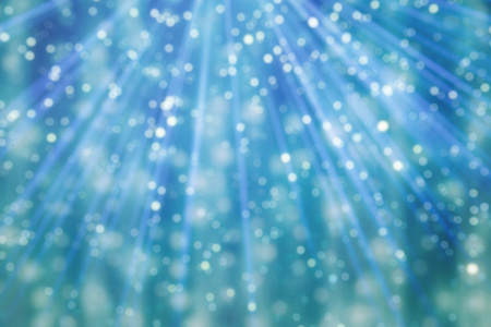 blue bokeh defocused light ray background. light shining from above on to blue green backgrounds.の写真素材