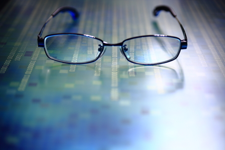 big data analysis. glasses placed on a LED digital panel display white light one and zero binary text number in moving motion pattern. modern technology blue block grid pattern backgroundsの写真素材