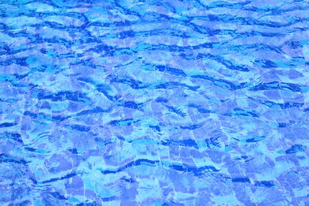 wave of swimming pool water surface. open water body blown by strong wind causing wave and ripple. blue ceramic tiles floor.の写真素材