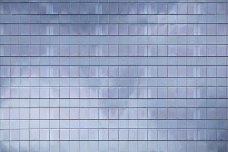 modern office building elevation. glass curtain wall repeating pattern reflecting cloud in the sky. city people in the architectural box.の写真素材
