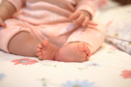 small baby sitting. close up image of baby leg and feet. healthy and happy infant sitting on her...
