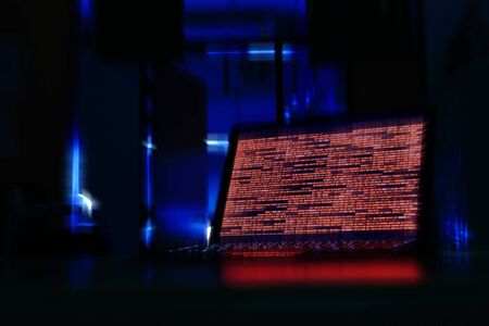 computer laptop in a dark room. computer displaying red code meaning problem, error, hacker or virus harming the system.の写真素材