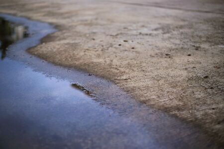 concrete road and flooding water. poor drainage system left puddle of inundated rain storm water on street surfaceの写真素材