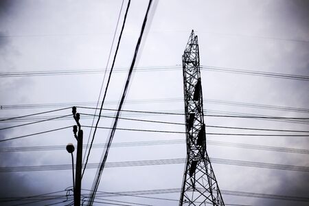 high voltage and home level Voltage electric power lines. silhouette electrical poles and cloudy dusk sky. city power supply and power consumption conceptsの写真素材
