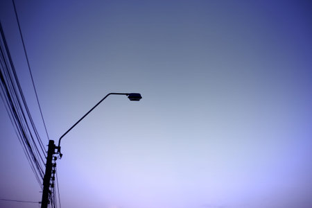 electric lamp post. silhouette light post and power lines at sunset. clear sky twilight hours. light...