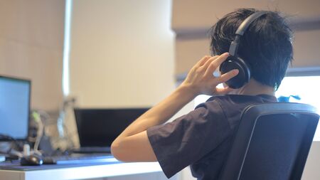 relaxing during work from home. man resting his head on hands while listening music on a headphone while watching computer notebook pc laptop monitor screen.の写真素材