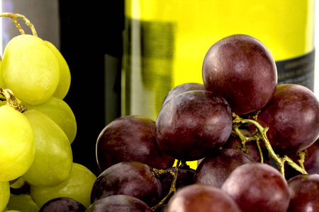 Closeup of two clusters of ripe grapes with wine bottle behindの写真素材