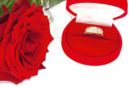 An engagement ring in display case with red rose lying alongsideの写真素材